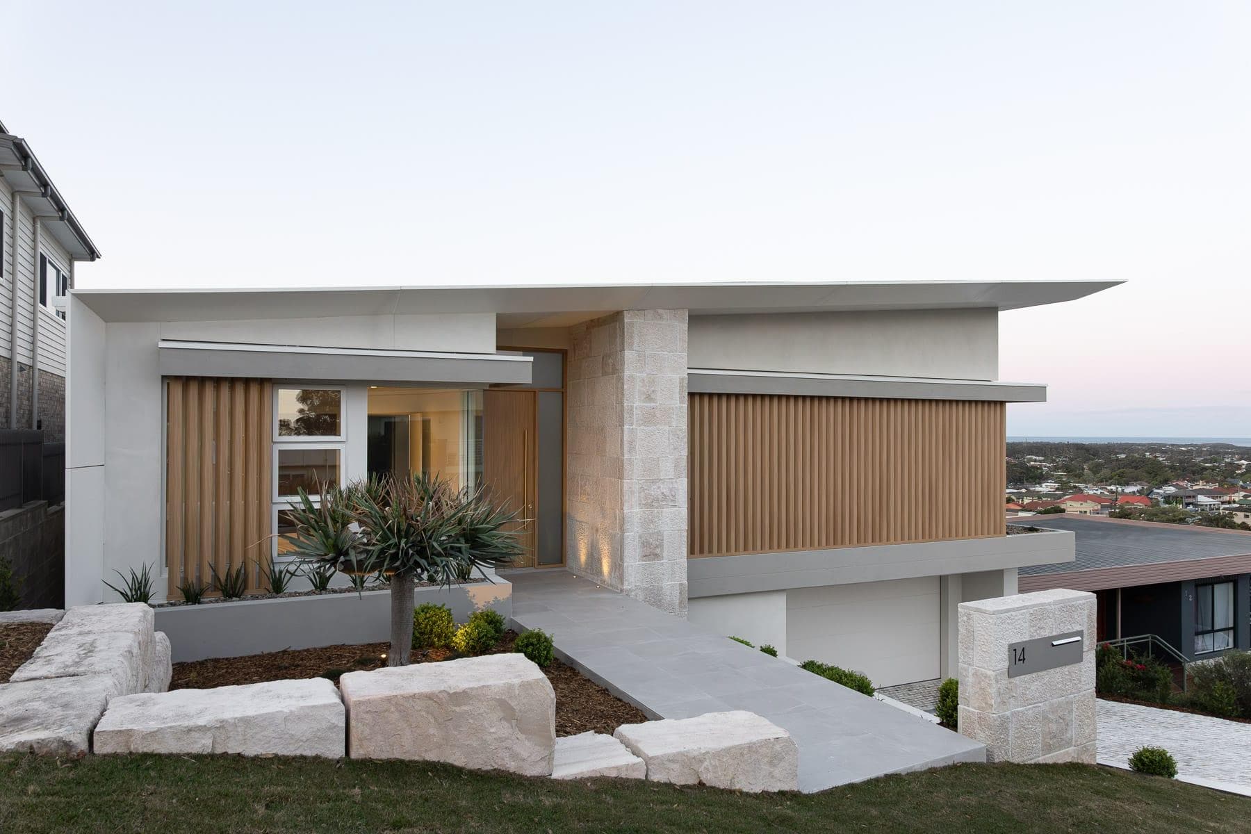 Entry façade of The Horizon Balgownie NSW at dusk highlighting ALPOLIC™ FR Milk White eaves and refined residential detailing